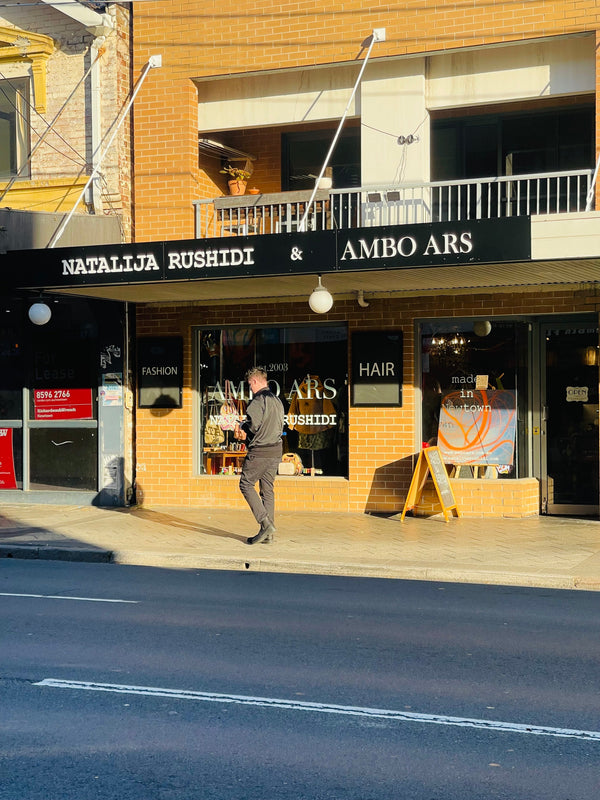 Front of of shop 1 80 Enmore Road. Natalija Rushidi & Ambo Ars sign in the window and awning. Afternoon sun, man walking on the street 