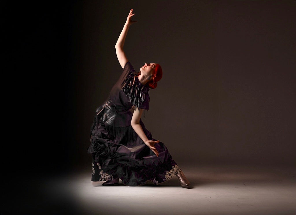Dancer in a dark dress with red hair against a dark background wearing Natalija Rushidi clothing 