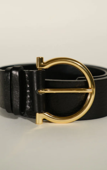 Black leather belt with a gold buckle on a light gray background